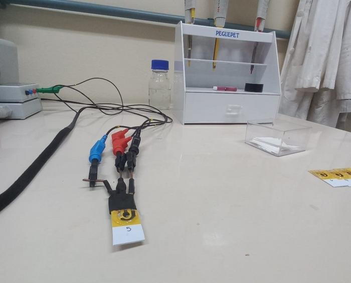 Laboratory workbench with multiple banana plug cables connected to a yellow tagged probe labeled 5 a white organizer and lab supplies in the background